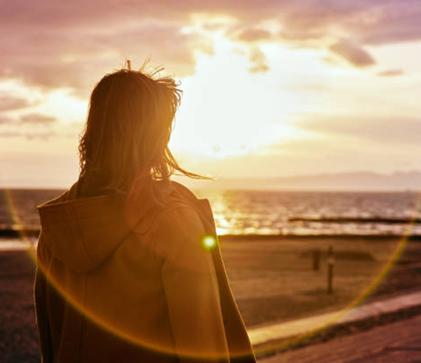 woman on the beach looking a sunset