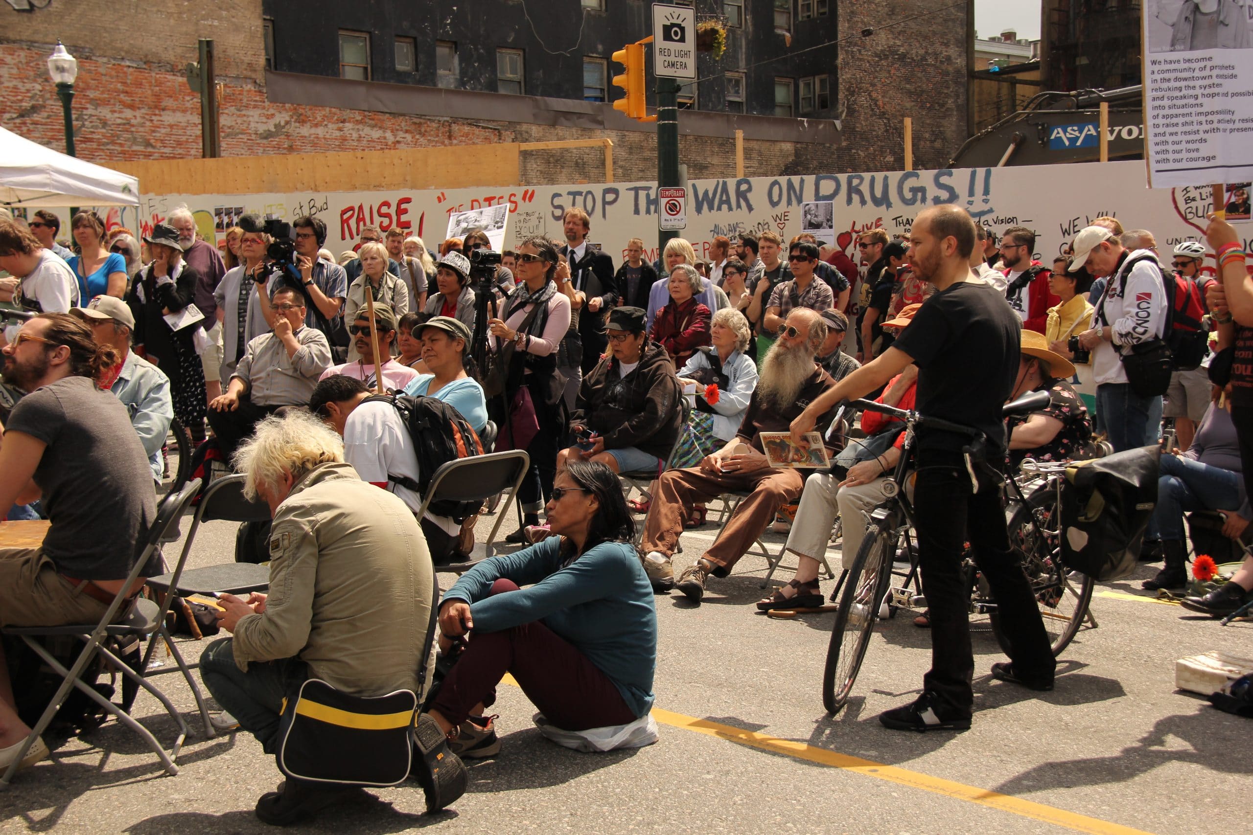 People gathered in the Downtown Eastside listening to a speaker
