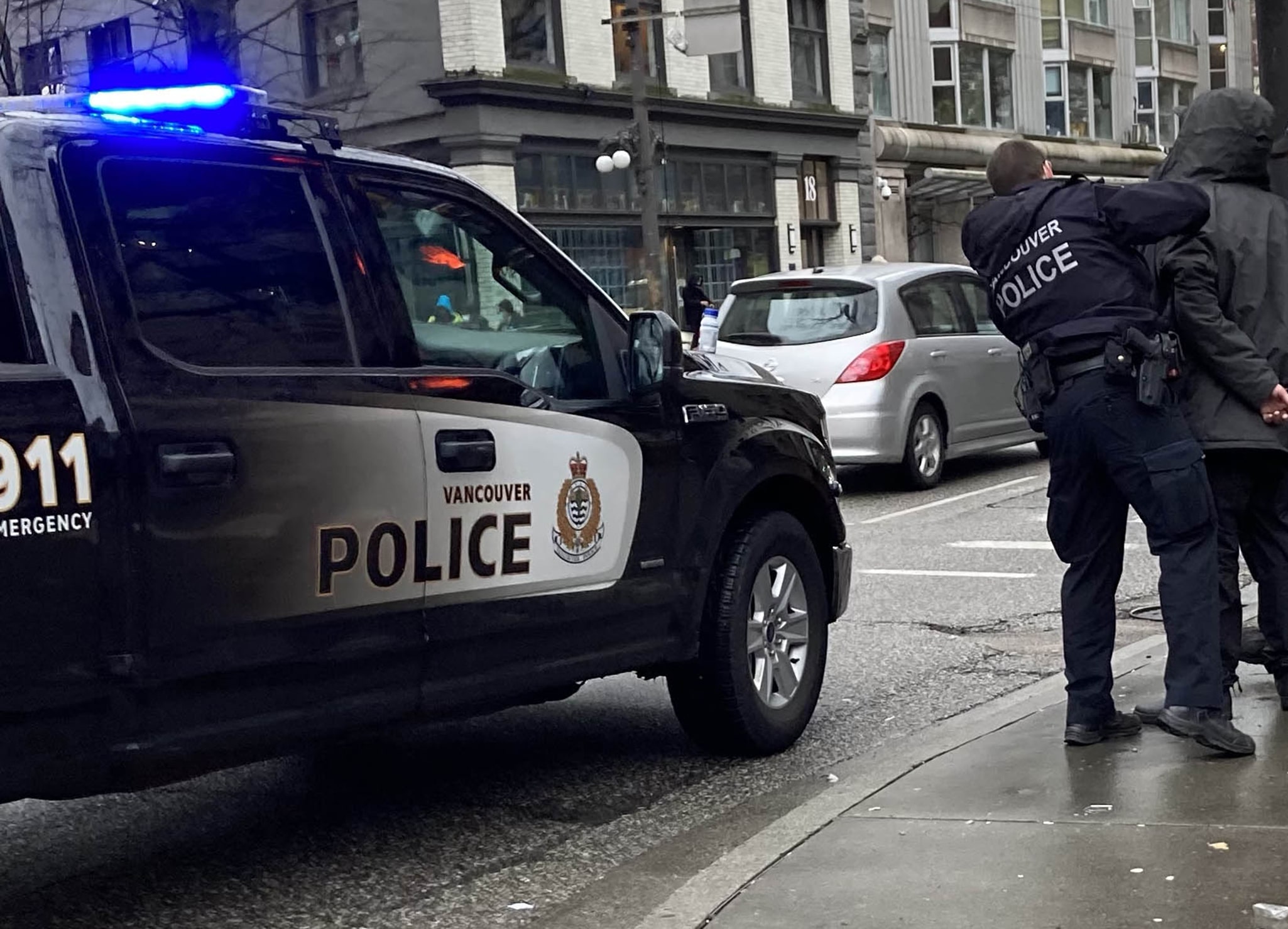 Vancouver police truck parked on side of the road while officer is arresting someone